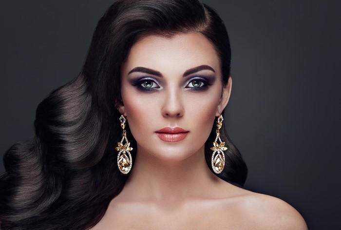 Woman with dark wavy hair and earrings