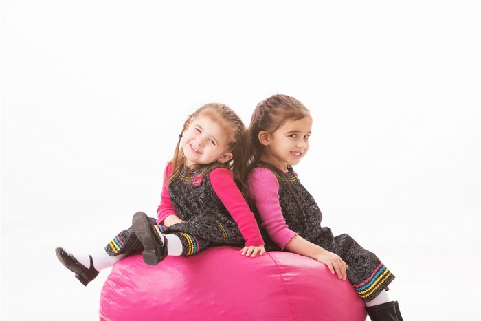 Two little girls sitting on a pink beanbag