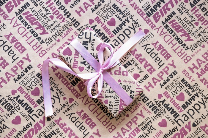 Gift box with ribbon on birthday wrapping paper