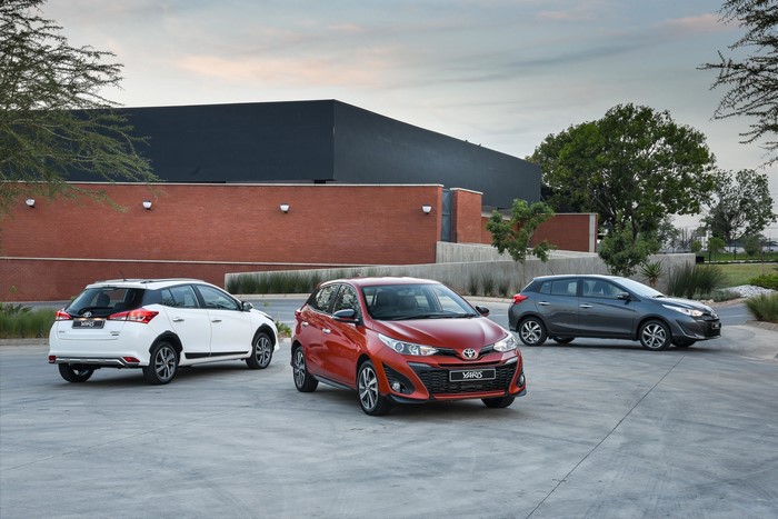 Three Toyota Yaris cars parked outside a modern building