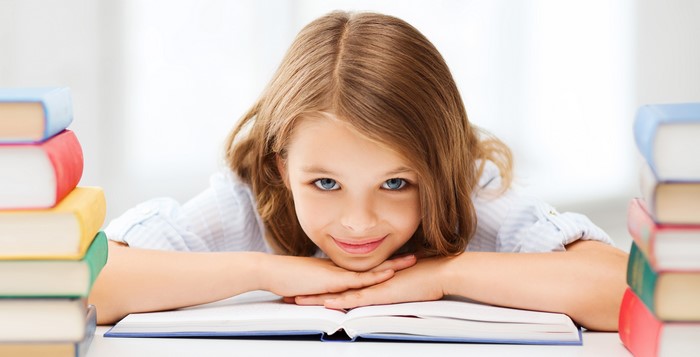 Young girl with books smiling at the camera