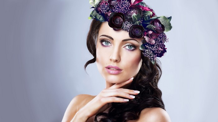 Brunette girl with floral wreath on gray background