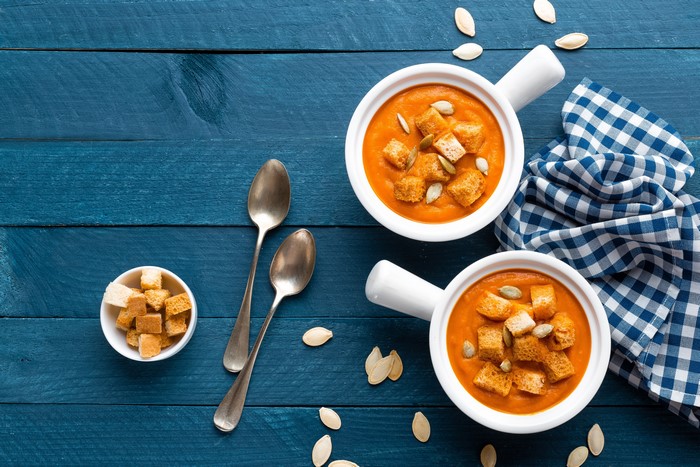 Two bowls of pumpkin soup with croutons and pumpkin seeds
