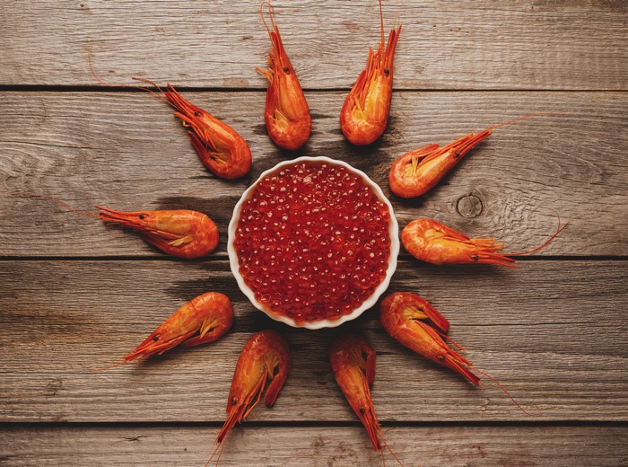 Shrimp and red caviar on wooden planks