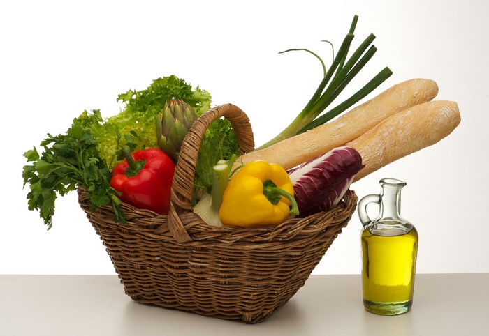 Vegetables and bread in a wicker basket with olive oil