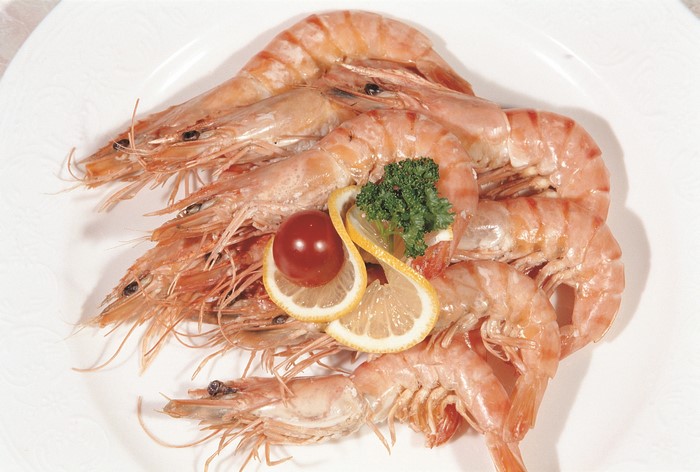 Plate of cooked shrimp with lemon and tomato garnish