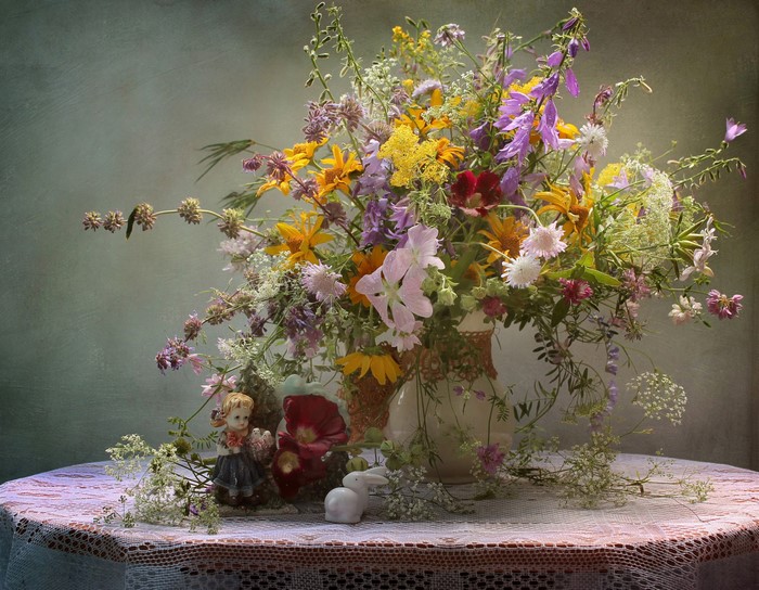 Wildflower bouquet in a vase with figurines on a table
