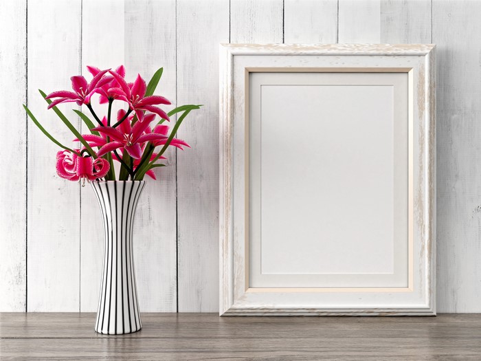 Pink lilies in a vase next to a picture frame
