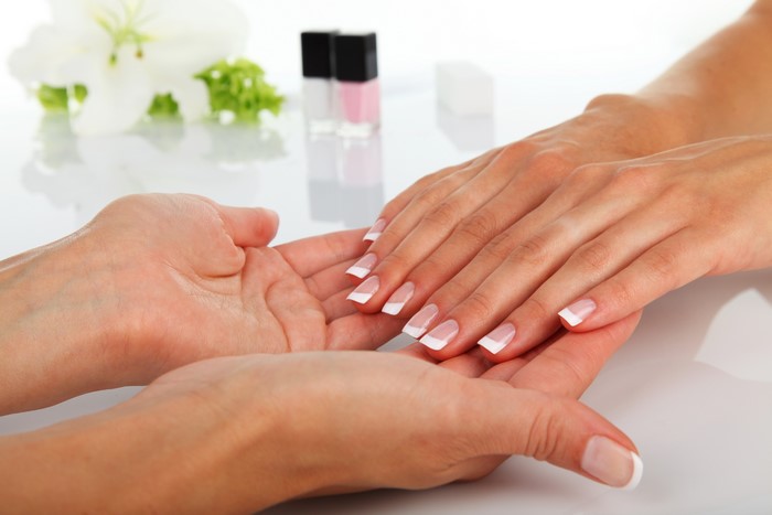 Hands receiving manicure with nail polish bottles