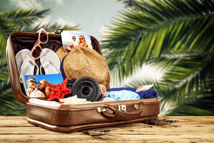Suitcase packed for vacation with hat and flip-flops