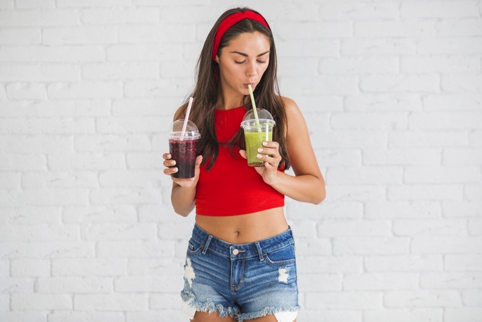 Woman in red top and denim shorts drinking juice