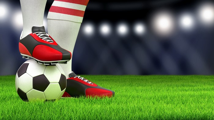 Soccer ball with player's foot on a grassy field