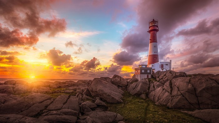 Lighthouse on rocky shore at sunset