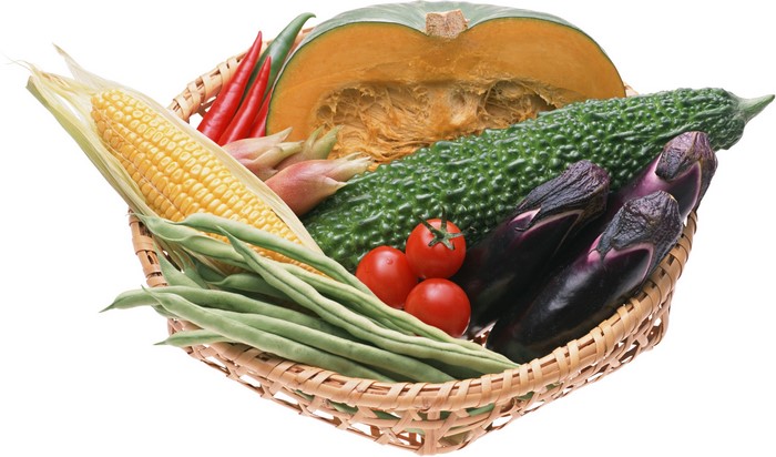 Basket of fresh vegetables including corn, eggplant, and pumpkin