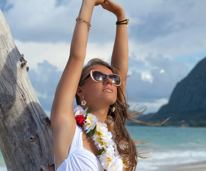 Woman with lei and sunglasses on beach
