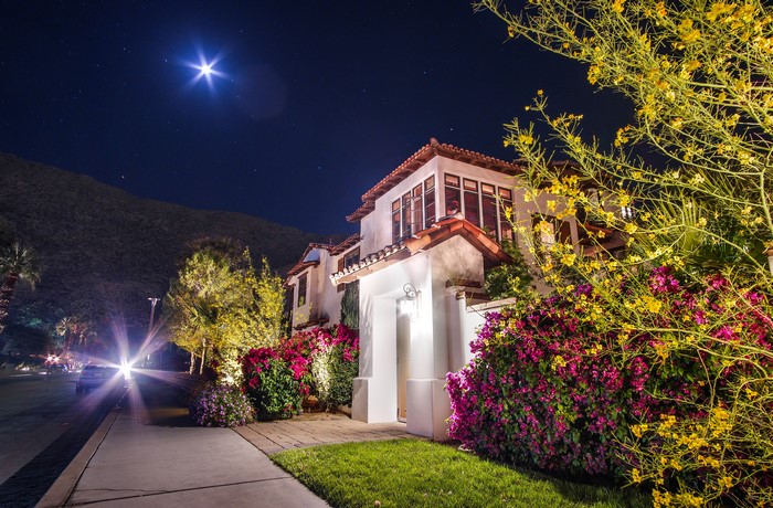 House at night with moon and car lights in California