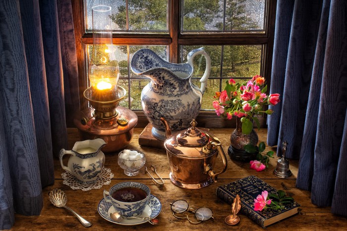 Still life with tea set, lamp, and flowers by window