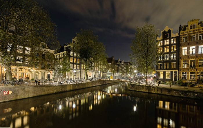 Amsterdam canal at night with illuminated houses and bridge