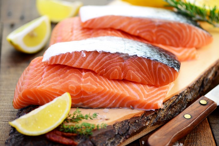 Salmon fillets with lemon and herbs on a wooden board