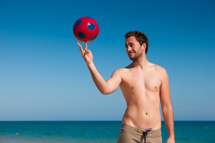 Man spinning a soccer ball on his finger at the beach