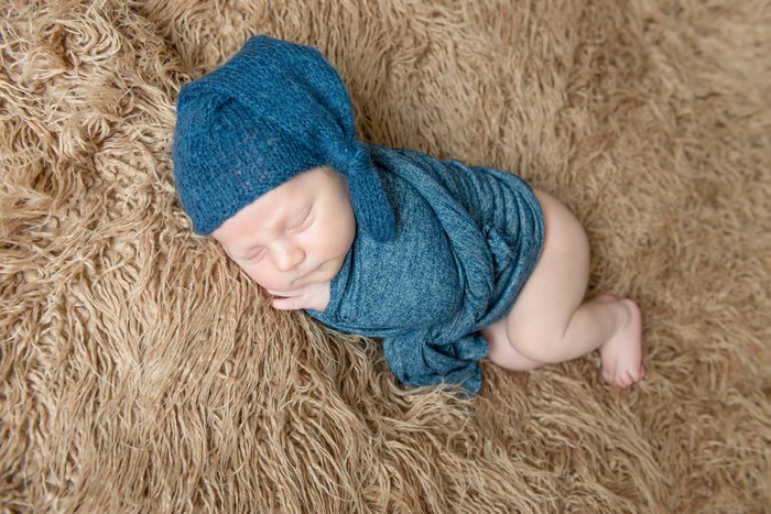 Newborn baby sleeping in a blue hat and swaddle