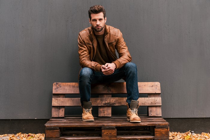 Man in Leather Jacket Sitting on Pallet Bench