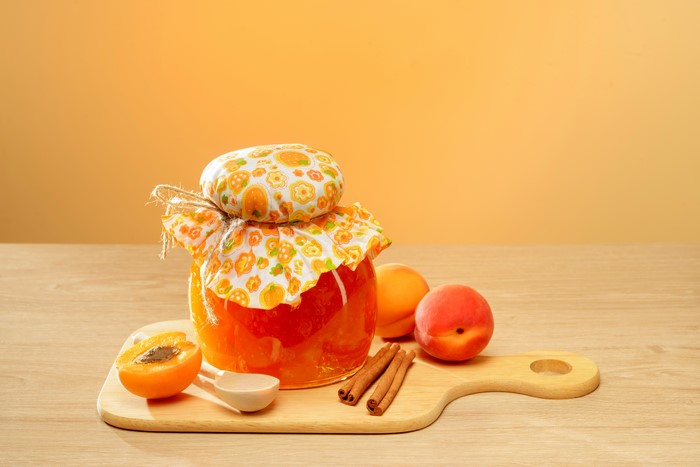 Apricot jam in a jar with apricots and cinnamon sticks