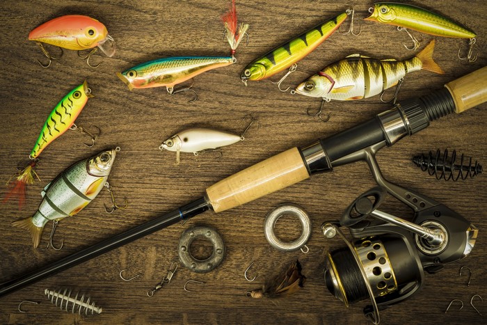 Fishing rod and lures on wooden background