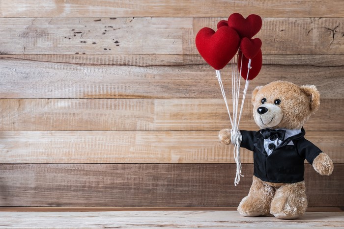 Teddy bear with heart balloons on wood planks