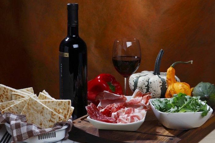 Bottle of red wine, charcuterie, bread, and pumpkins