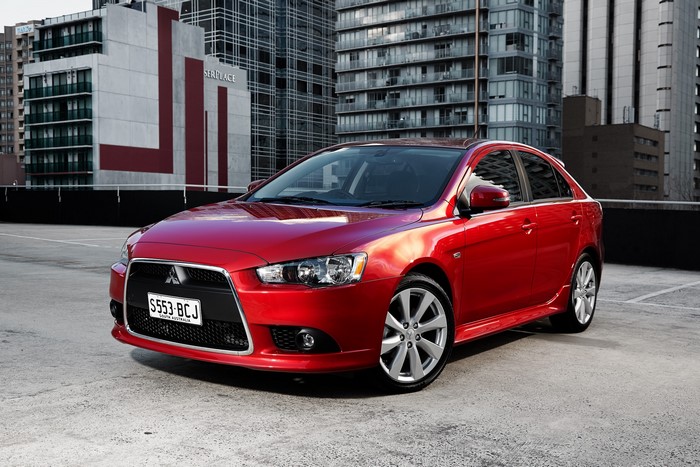 Red Mitsubishi Lancer sedan parked in a city