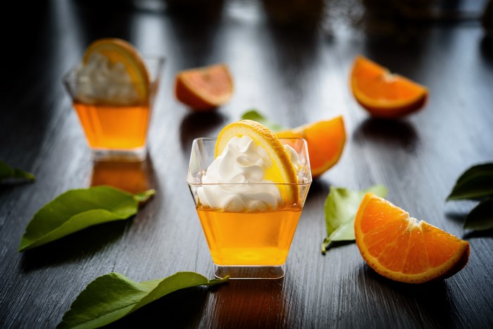 Orange jelly desserts with whipped cream and orange slices