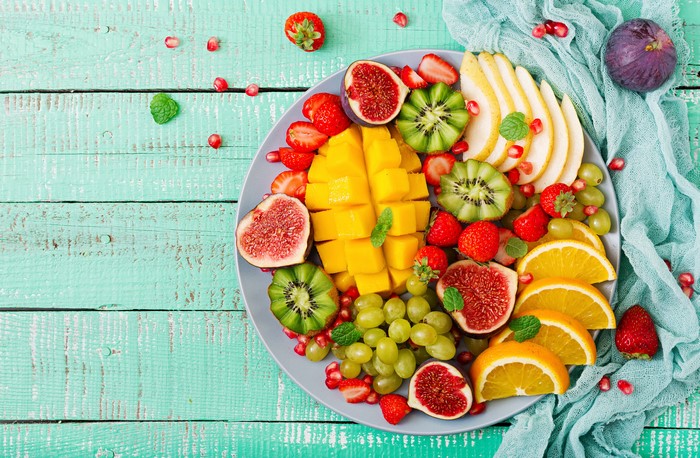 Fruit platter with mango, figs, kiwi, oranges, strawberries, grapes, and pears