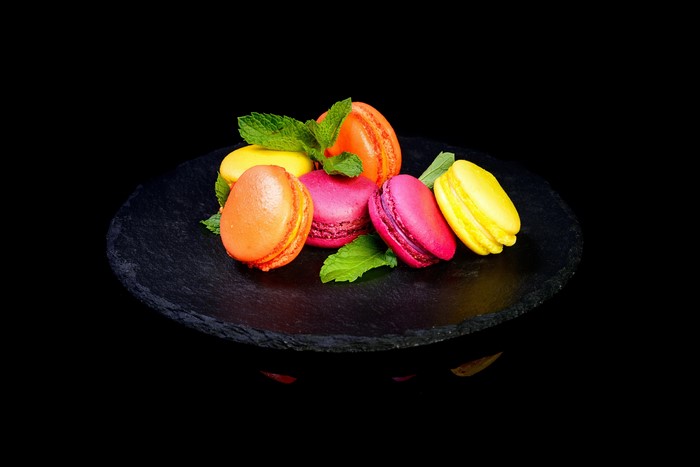 Colorful macarons with mint leaves on black slate