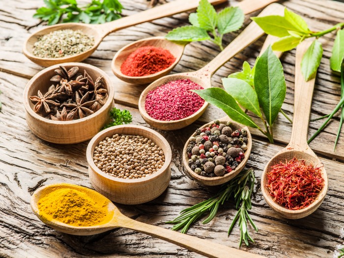 Various spices in wooden spoons and bowls