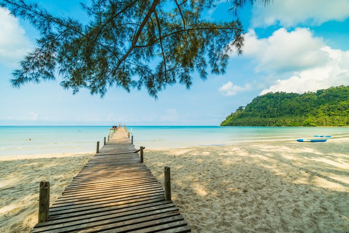 Wooden pier on a tropical beach with kayaks