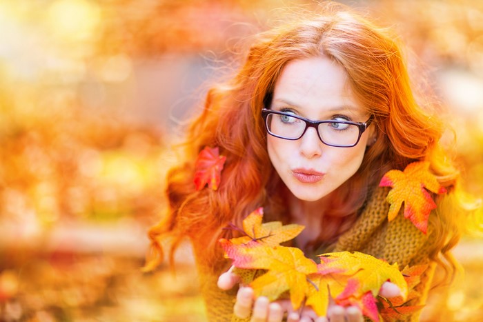 Redhead girl with glasses in autumn foliage