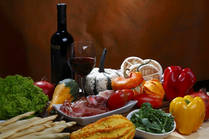Still life with wine, pumpkins, bell peppers, and ham