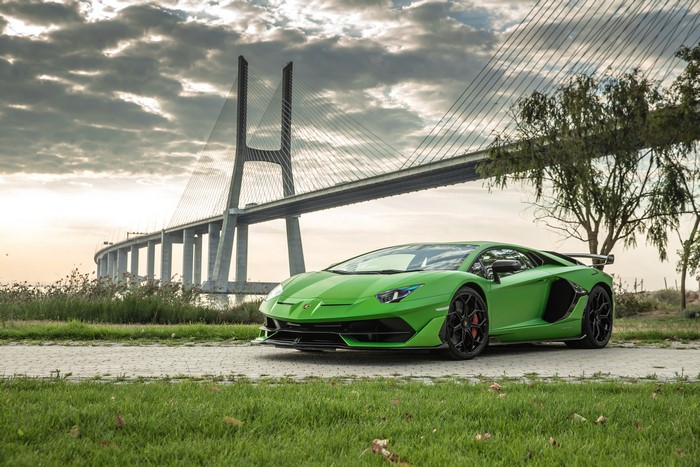 Green Lamborghini Aventador SVJ parked near a bridge