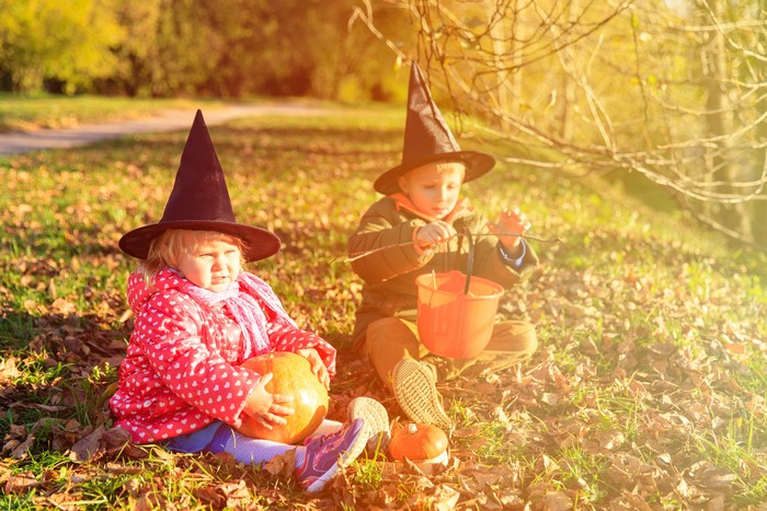 Two children in witch hats with pumpkins for Halloween