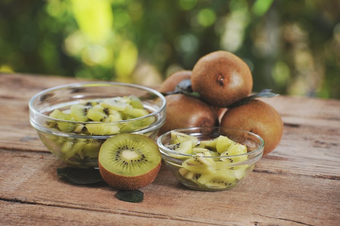 Kiwi fruit sliced and whole on wooden planks