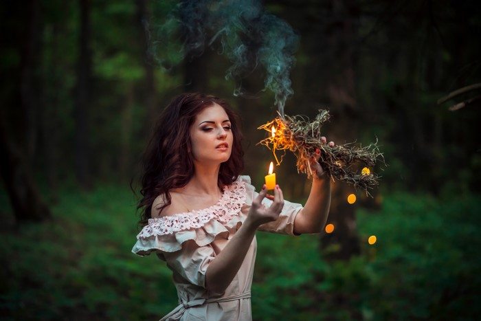Woman with candle and burning effigy in forest