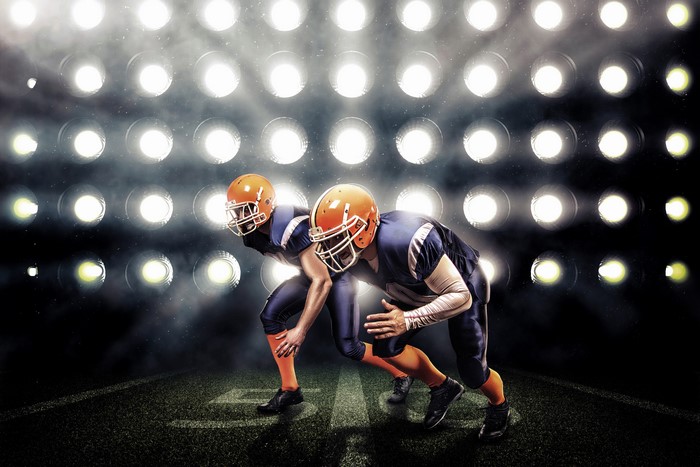 Two American football players in uniform and helmets