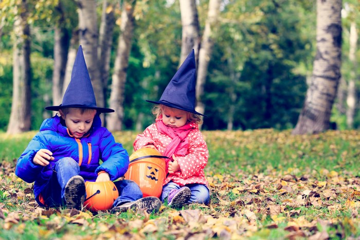 Two children in witch hats with Halloween pumpkins