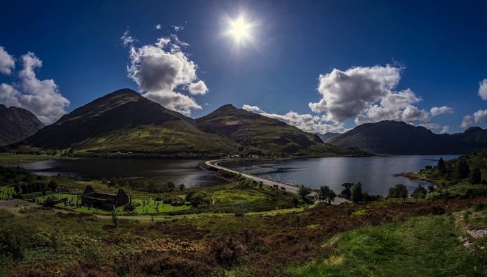 Road crossing a lake with mountains and ruins in Scotland