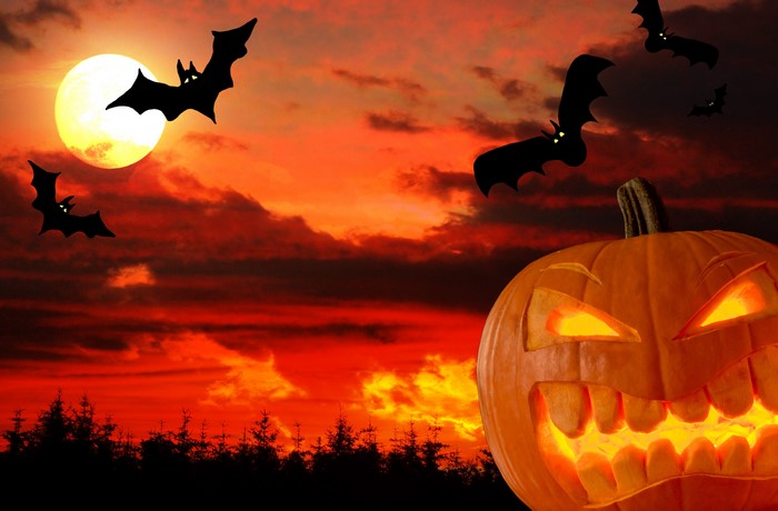 Halloween pumpkin and bats against a full moon sky