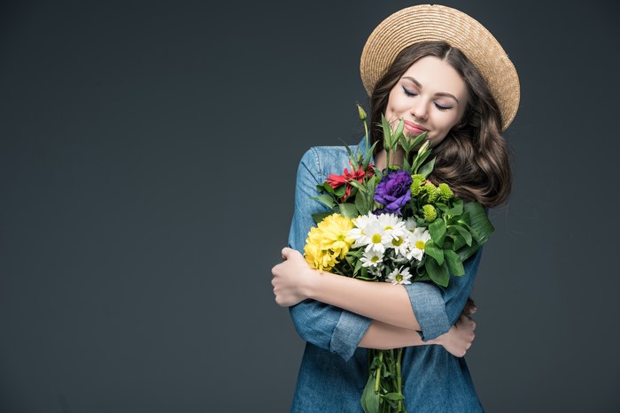 Woman in Straw Hat Holding a Bouquet of Flowers