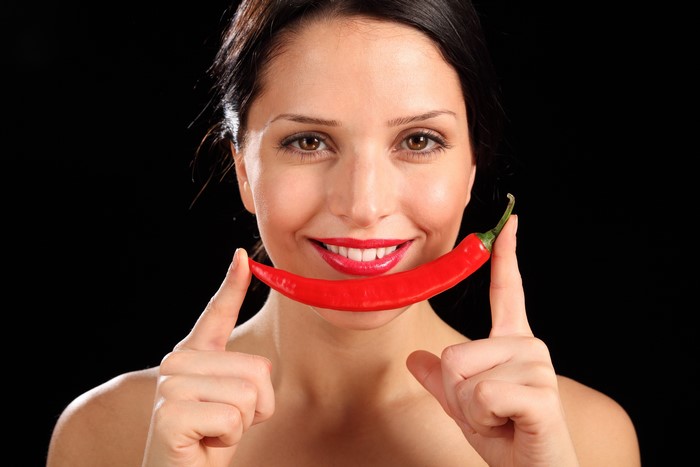 Woman with red chili pepper on black background