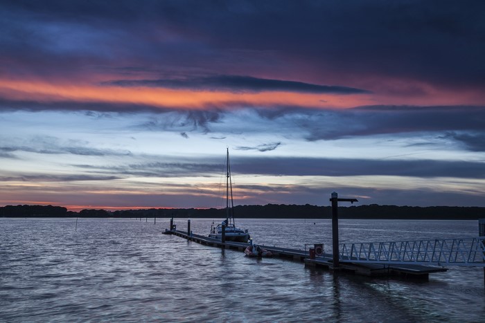 Boat docked at a pier during sunset over water