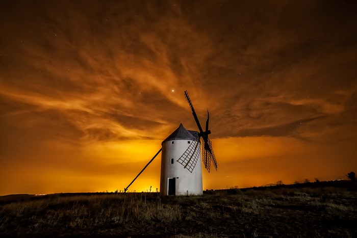 Windmill under a dramatic orange sky at night